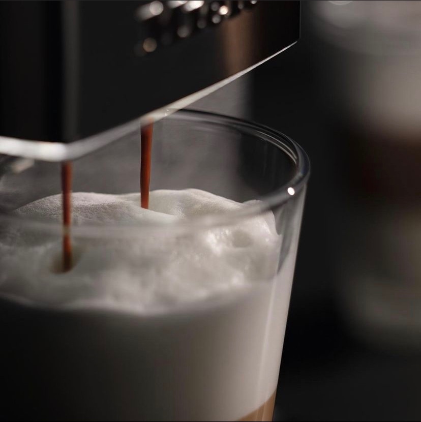  Close-up of espresso pouring into a glass of frothed milk