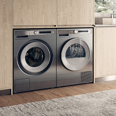 White stacked washer and dryer built into wood laundry cabinetry