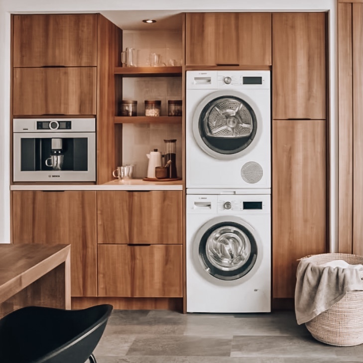 White stacked washer and dryer built into wood laundry cabinetry