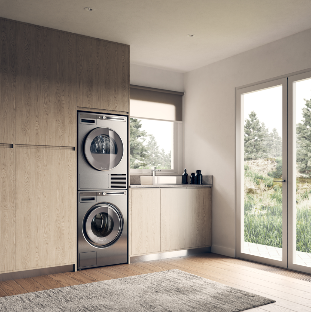 Stainless steel stacked washer and dryer in a bright laundry nook with a window