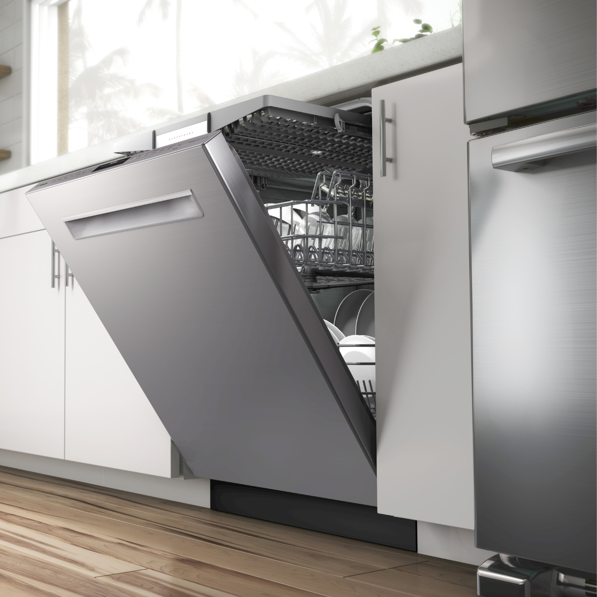 A stainless steel dishwasher with its door open at an angle, revealing loaded racks with dishes and glassware, installed under a white countertop in a modern kitchen with light hardwood floors.